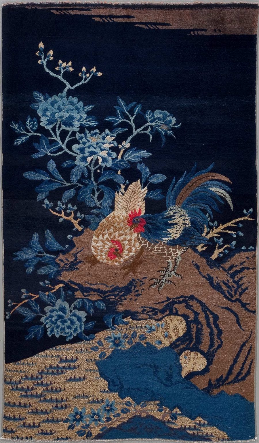 Orientteppich mit einem Hahn und floralen Motiven in Blau- und Brauntönen auf dunkelblauem Hintergrund.