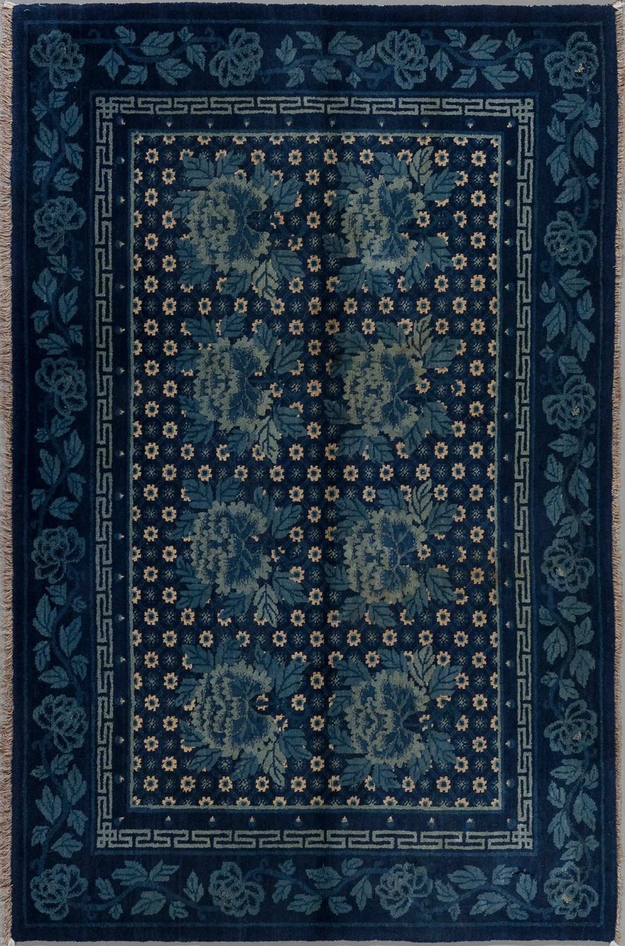 Dunkelblauer Teppich mit traditionellem floralen Muster und griechischem Schlüsselrand in diversen Blautönen und Akzenten in Beige.