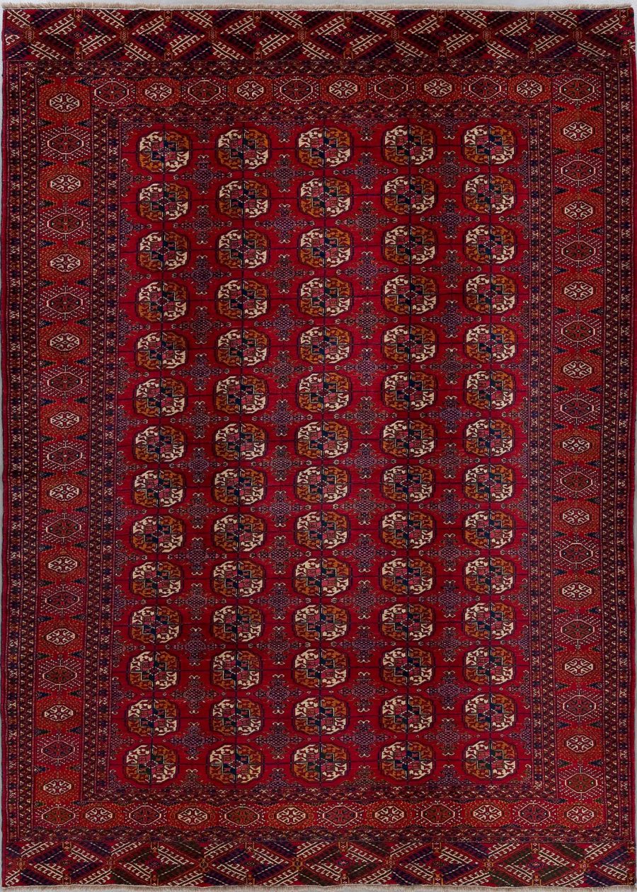 Traditioneller, rechteckiger, handgewebter Teppich mit dichtem Muster aus geometrischen Formen und mehreren Bordüren in Rot-, Blau- und Beigetönen.