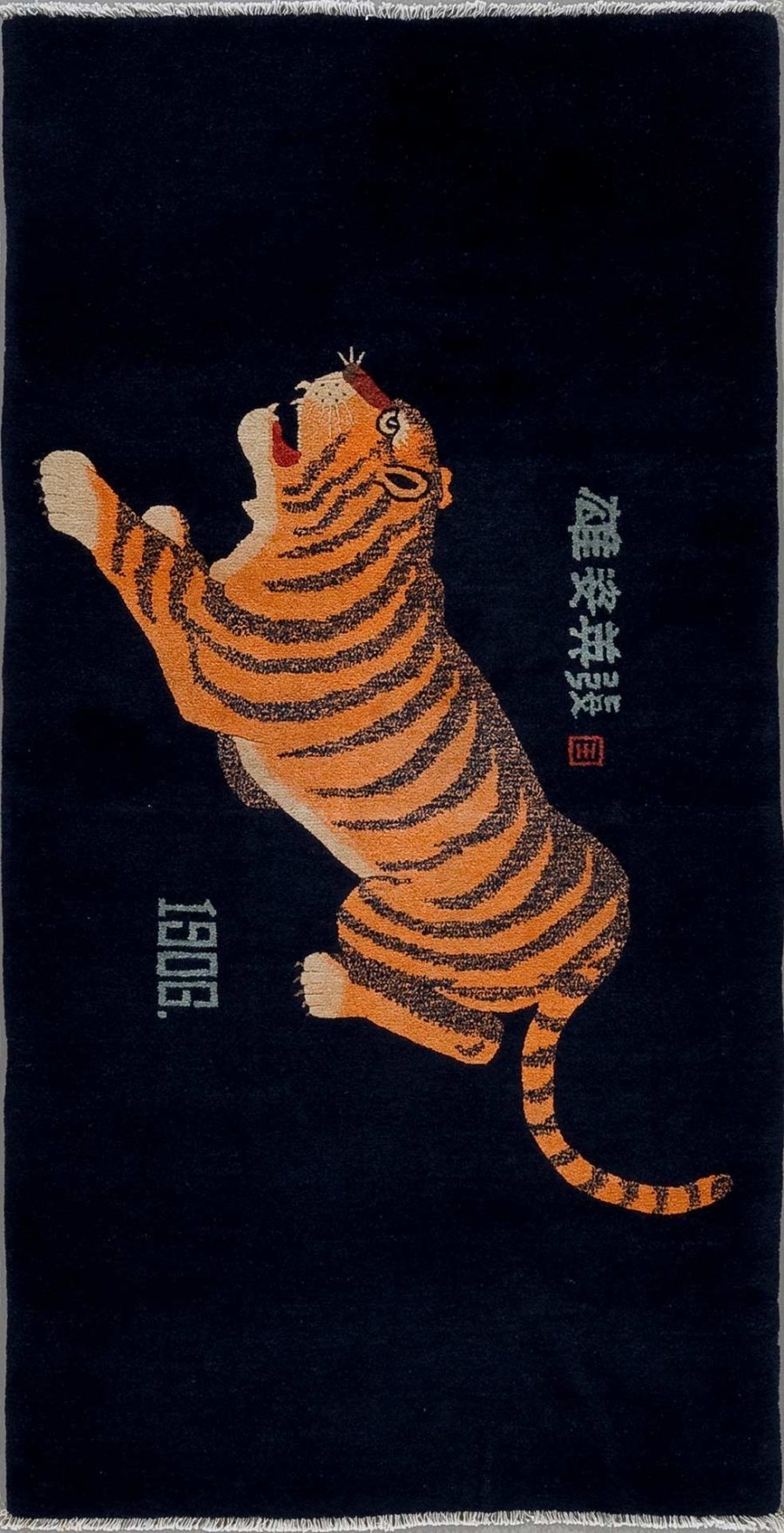 Antik wirkender Wandteppich mit einem springenden Tiger in Orange und Schwarz vor einem dunklen Hintergrund und asiatischen Schriftzeichen am rechten Rand.