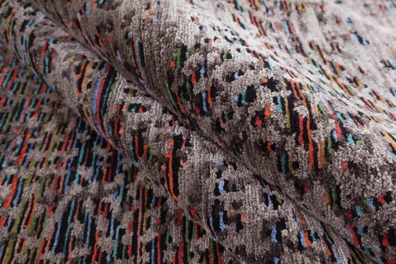 Nahaufnahme eines strukturierten Teppichs mit buntem, abstraktem Muster.