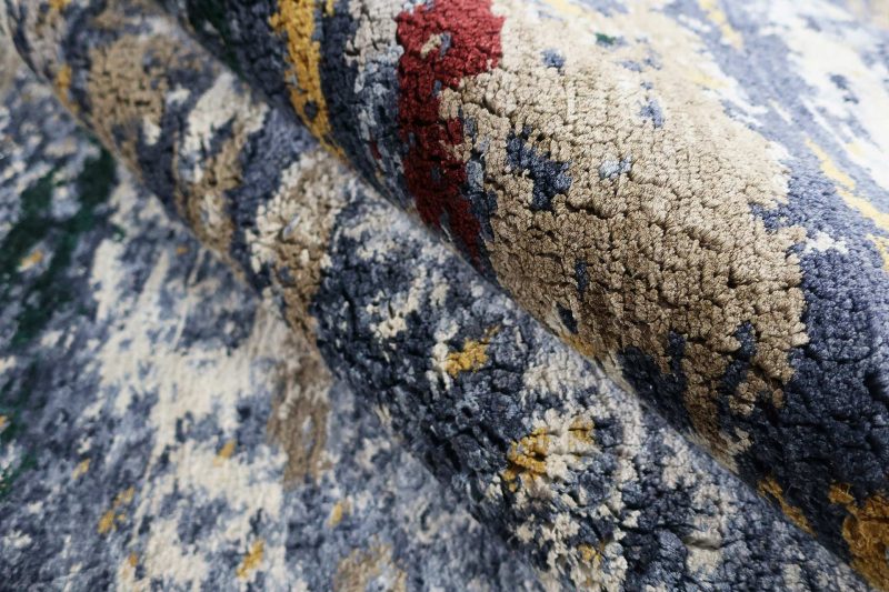 Nahaufnahme eines strukturreichen, gemusterten Teppichs in verschiedenen Farben wie Blau, Gelb und Rot mit Fokus auf die Textur des Gewebes.