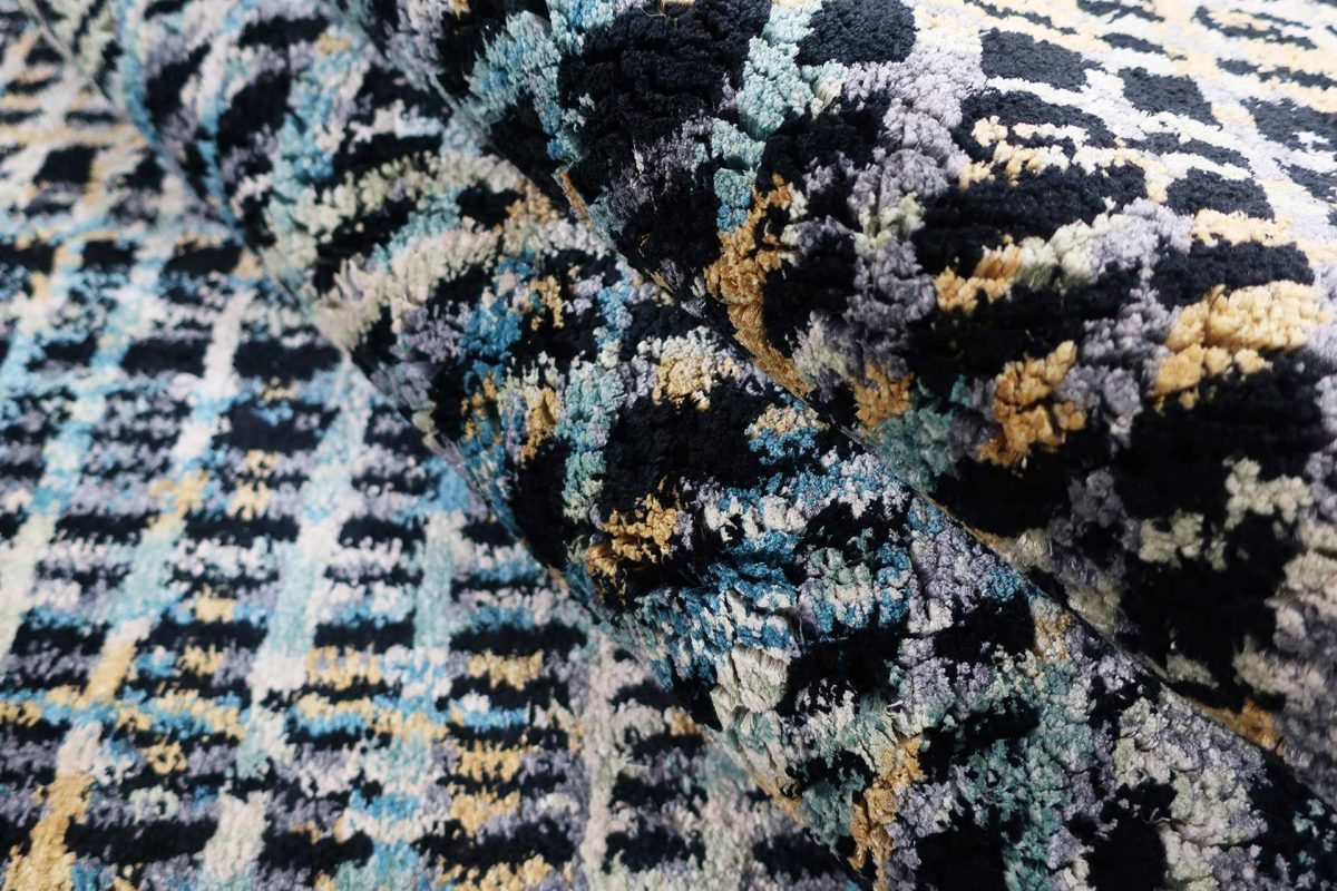 Nahaufnahme eines texturierten Teppichs mit abstraktem Muster in Schwarz, Blau, Grau und Gelbtönen.