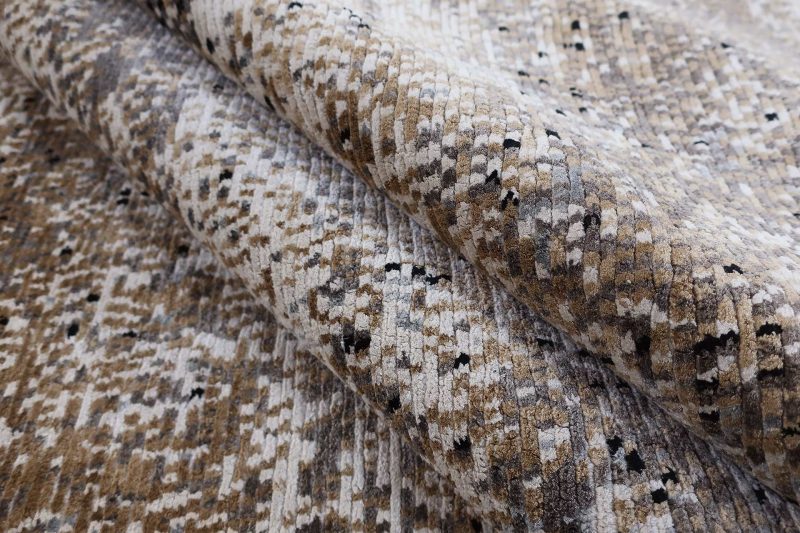 Nahaufnahme von einem gefalteten Teppich mit einem abstrakten Muster in Erdtönen.