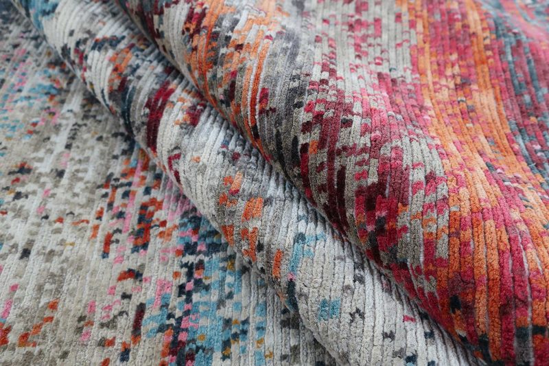 Gefalteter, bunter Teppich mit verschiedenen Mustern und Texturen.