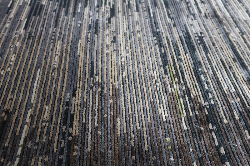Nahaufnahme eines strukturierten Teppichs mit horizontalen Streifen in verschiedenen Grau- und Grüntönen.