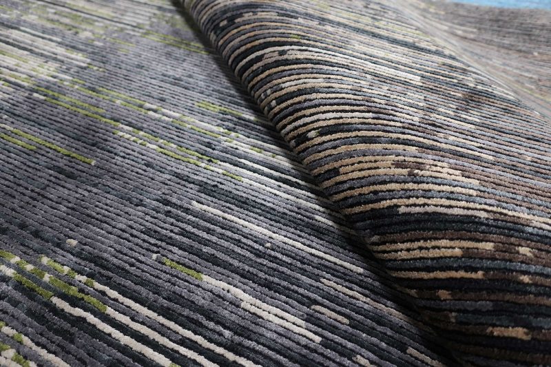 Nahaufnahme eines strukturierten Teppichs mit horizontalen Streifen in verschiedenen Grau- und Grüntönen.
