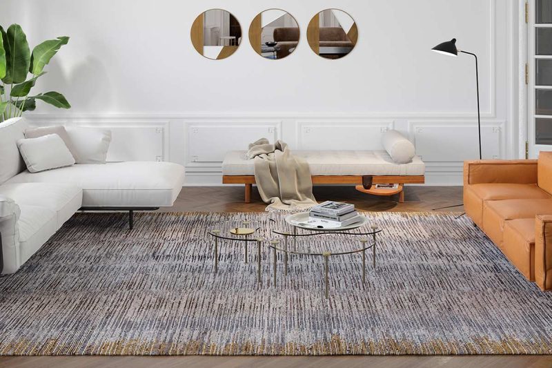 Modern gestaltetes Wohnzimmer mit weißem L-förmigen Sofa und orangefarbenem Sofa, strukturiertem Teppich, runden Metallbeistelltischen, einer Stehlampe, Wandspiegeln, hohen Fenstern und Zimmerpflanze.