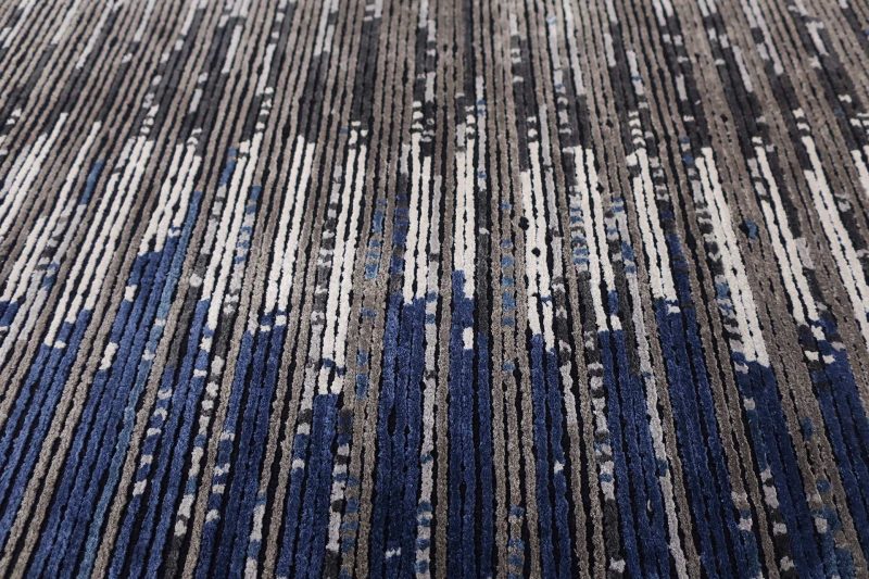 Strukturierte Nahaufnahme eines Teppichs mit abstraktem Muster in Blau-, Grau- und Beigetönen.