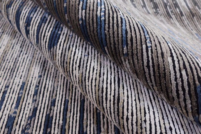 Strukturierte Nahaufnahme eines Teppichs mit abstraktem Muster in Blau-, Grau- und Beigetönen.