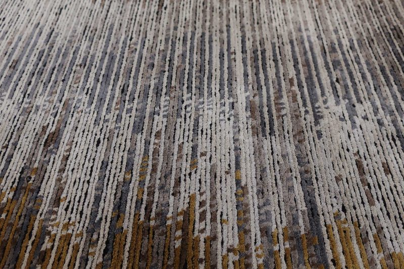 Nahaufnahme einer strukturierten Teppichoberfläche mit einem abstrakten Muster aus verschiedenen Grau-, Braun- und Ockertönen.