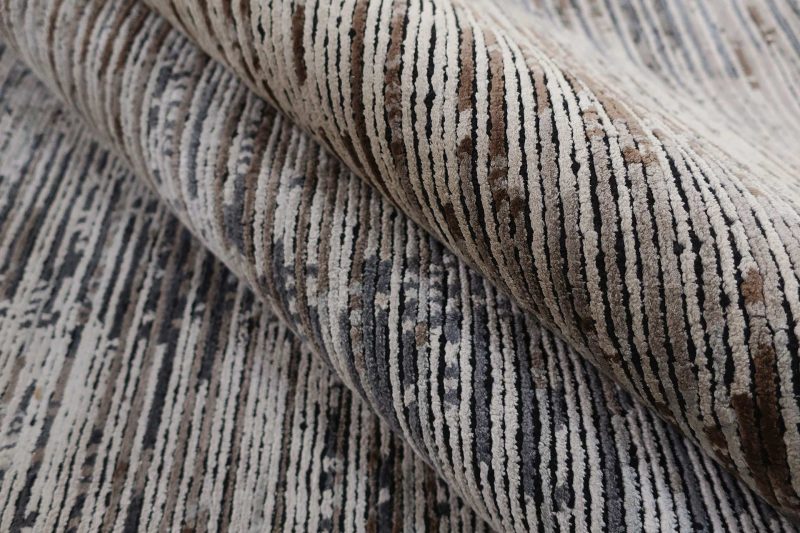 Nahaufnahme eines Teppichs mit einem Muster aus verschiedenen Grautönen und Strukturen.