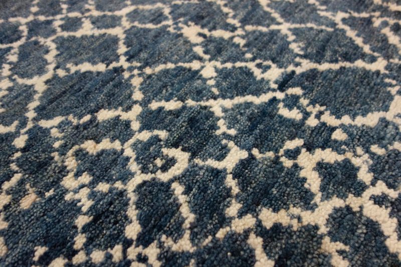 Nahaufnahme eines strukturierten Teppichs mit einem abstrakten Muster in verschiedenen Blautönen und Cremeweiß.