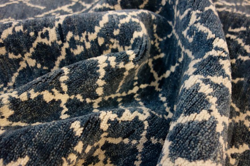 Nahaufnahme eines strukturierten Teppichs mit einem abstrakten Muster in verschiedenen Blautönen und Cremeweiß.