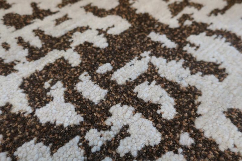 Nahaufnahme eines gemusterten Teppichs mit unregelmäßigen dunkelbraunen und weißen Formen.