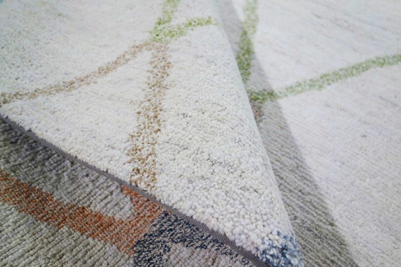 Nahaufnahme eines texturierten Teppichs mit einem abstrakten Muster aus mehrfarbigen Linien in Blau, Grün und Orange.