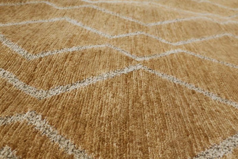 Nahaufnahme eines strukturierten Teppichs mit geometrischem Muster in Beige- und Cremetönen.
