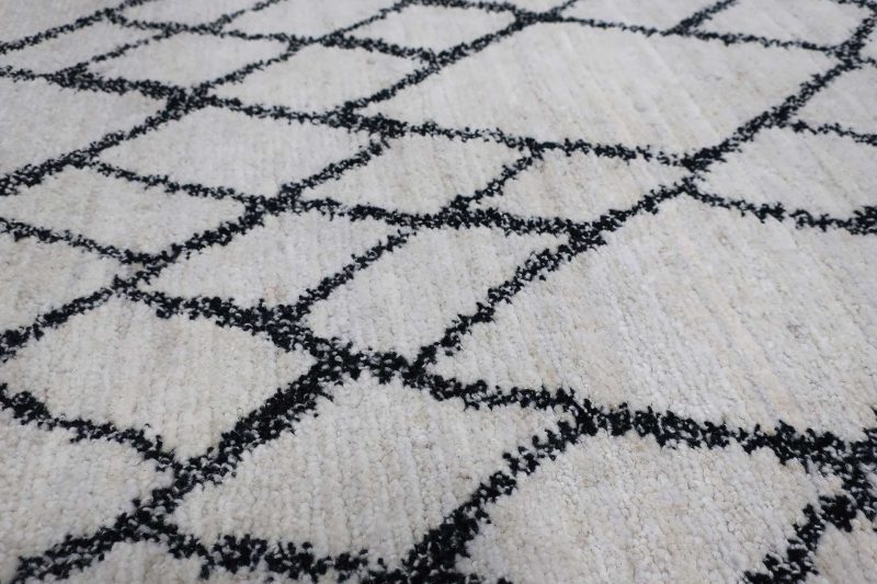 Weißer Teppich mit schwarzem Rautenmuster.