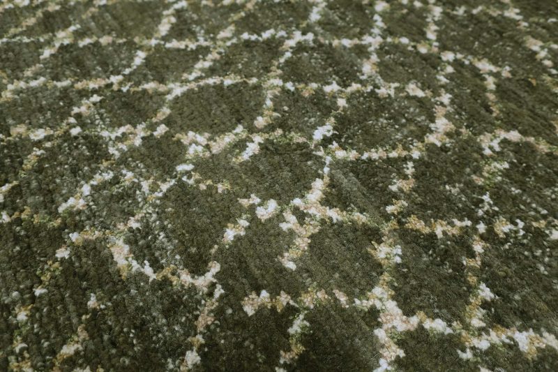 Nahaufnahme eines gemusterten Teppichs in verschiedenen Grüntönen mit weißen und beigefarbenen Akzenten.