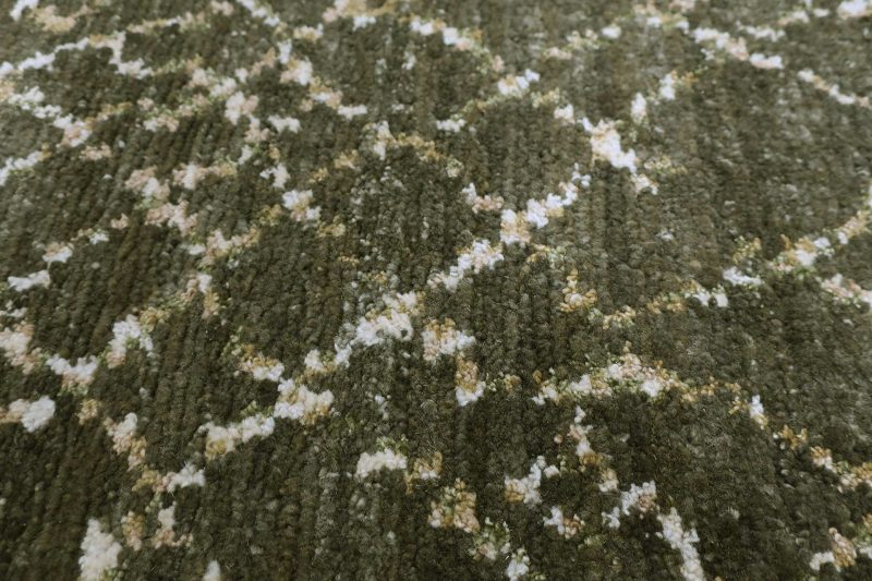 Nahaufnahme eines gemusterten Teppichs in verschiedenen Grüntönen mit weißen und beigefarbenen Akzenten.