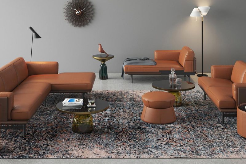 Modernes Wohnzimmer mit großem Fenster und Seeblick, ausgestattet mit mehreren cognacfarbenen Ledersofas und Sesseln, einem bunten Teppich, runden Glastischen und dekorativen Pflanzen, ergänzt durch minimalistische Steh- und Tischlampen.