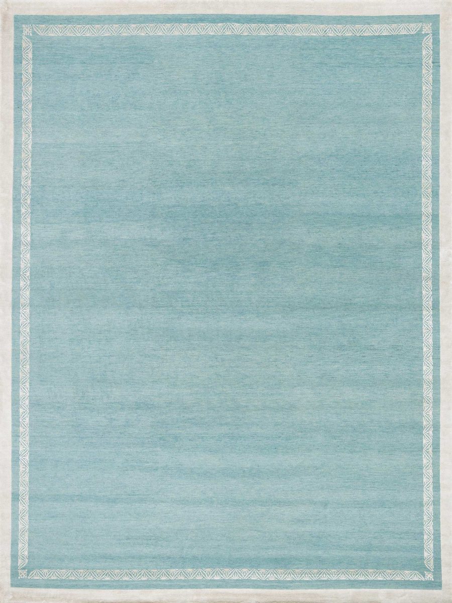 Ein moderner, einfarbiger hellblauer Teppich mit einem dunkleren Rahmen und dezentem geometrischem Muster an den Rändern, ausgelegt auf einem ebenen Untergrund.